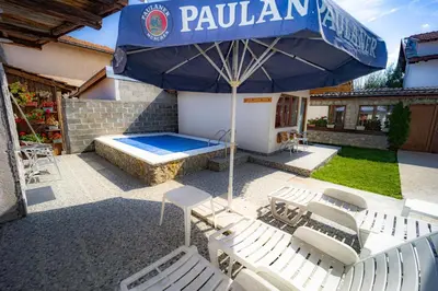 a patio with a blue umbrella and chairs and a pool at Banya Guest Rooms 23 in Banya