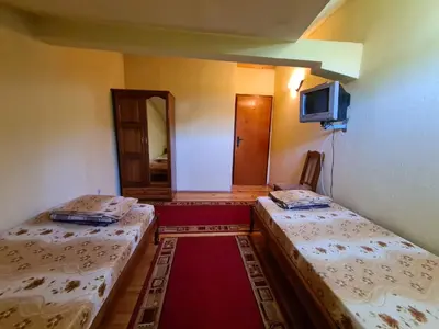 a room with two beds and a tv on the wall at Villa Mura in Razlog