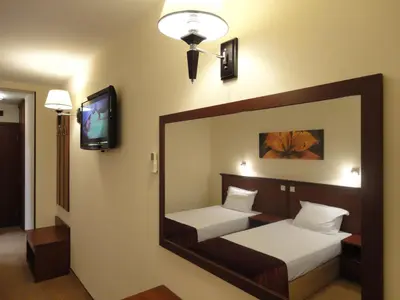 a mirror in a room with two beds and a tv at Favorit Hotel in Sofia