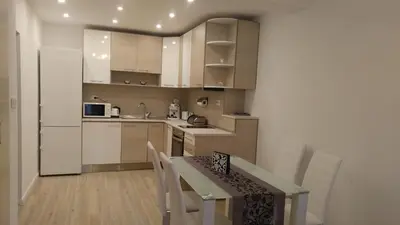 a kitchen with white cabinets and a table with chairs at Modern apartment Sofia center in Sofia