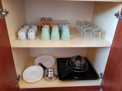 a cupboard with plates and jars and a stove at Oleander Rooms & Apartment in Sofia