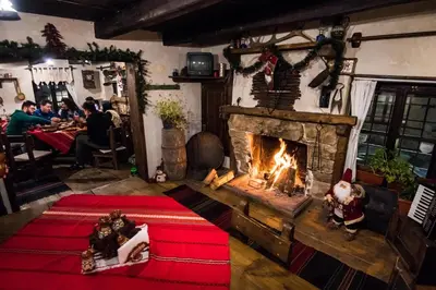 a living room with a fireplace and people sitting at tables at Banskovilla Zlateva House in Bansko