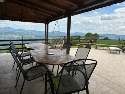 a wooden table and chairs on a patio at Karadzhovata Kashta in Zlatograd