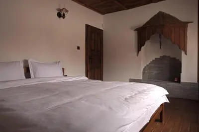 a bedroom with a white bed and a fireplace at ЧОЛАКОВАТА КЪЩА in Koprivshtitsa