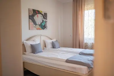 a bed with white sheets and blue pillows in a bedroom at KATERINA guest house in Kocherinovo