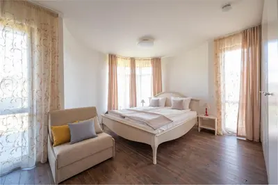 a bedroom with a large bed and a chair at KATERINA guest house in Kocherinovo