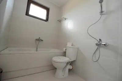 a white bathroom with a toilet and a bath tub at KATERINA guest house in Kocherinovo