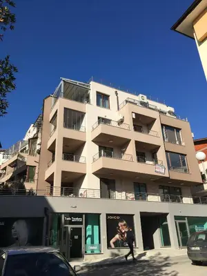a tall building with a person walking in front of it at Apartments Park Place in Sandanski
