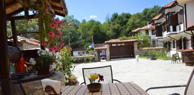 a patio with a table and a courtyard with flowers at Family Hotel Dinchova kushta in Rozhen