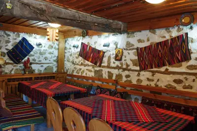 a restaurant with two tables and chairs in a room at Family Hotel Dinchova kushta in Rozhen