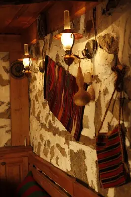 a room with a stone wall with a curtain and lights at Family Hotel Dinchova kushta in Rozhen