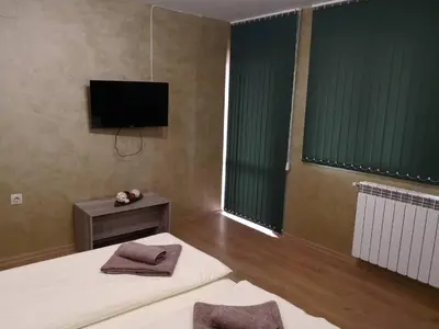 a bedroom with two beds and a flat screen tv at Yurukovata kashta in Koprivshtitsa