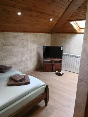 a bedroom with a bed and a flat screen tv at Yurukovata kashta in Koprivshtitsa