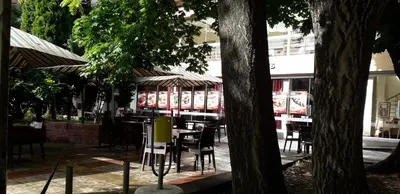 a restaurant with tables and chairs and umbrellas at Heat Complex Family Hotel in Peshtera