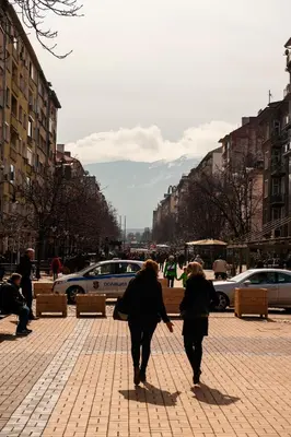 two people walking down a brick sidewalk in a city at Vitosha Blvd - Attic Studio in Sofia