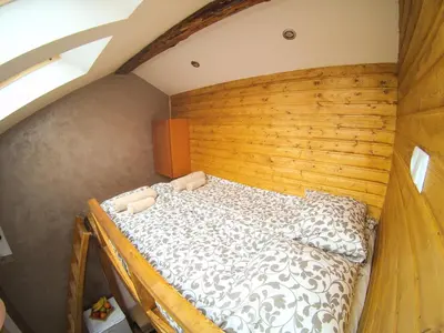 a large bed in a room with a wooden wall at Vitosha Blvd - Attic Studio in Sofia