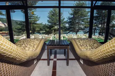 two chairs and a table in a room with windows at Family Hotel Hebar in Batak