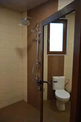 a bathroom with a shower with a toilet and a window at Ваканционно селище Ива in Sarnitsa