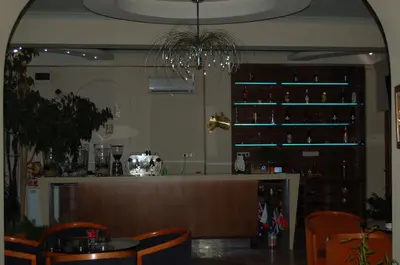 a restaurant with a bar with orange chairs and a chandelier at Kniaz Boris Hotel in Sofia