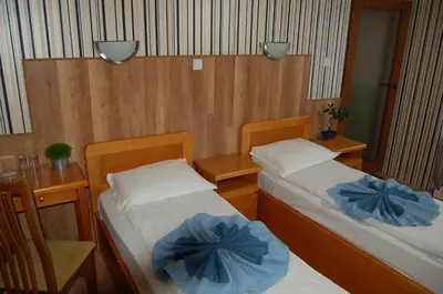 two beds in a small room with a table and chairs at Kniaz Boris Hotel in Sofia