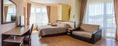 a bedroom with a bed and a chair and a desk at Семеен хотел 