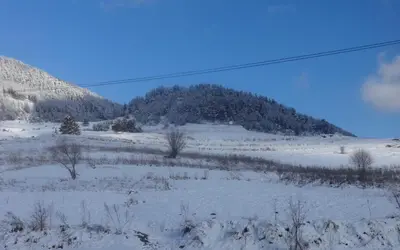 a snow covered field with a mountain in the background at Семеен хотел 