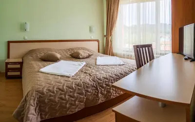 a bedroom with a bed with two pillows and a table at Семеен хотел 