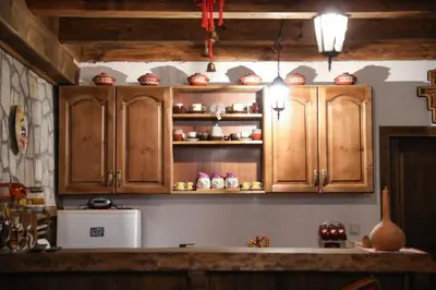 a kitchen with wooden cabinets and a white refrigerator at Тодорината къща in Leshten