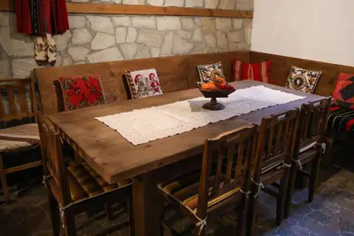 a wooden table with chairs and a bowl of fruit on it at Тодорината къща in Leshten