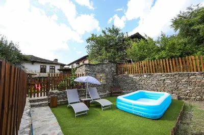a backyard with a pool and chairs and an umbrella at Тодорината къща in Leshten