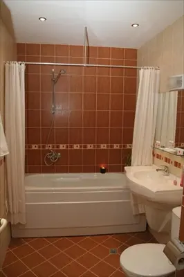 a bathroom with a tub and a toilet and a sink at Hotel Real in Plovdiv
