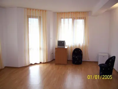 a living room with two windows and a desk with a television at Hotel Gazei in Bansko