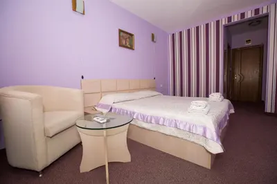 a bedroom with a bed and a chair at Семеен Хотел Сокол in Sandanski