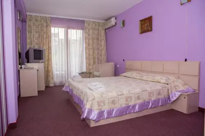 a bedroom with a bed with purple walls and a television at Семеен Хотел Сокол in Sandanski