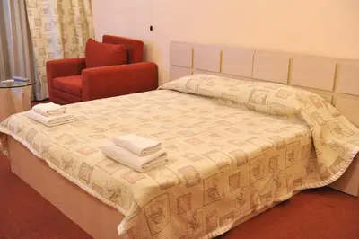 a bedroom with a bed and a chair with towels on it at Семеен Хотел Сокол in Sandanski