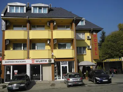 a yellow building with cars parked in front of it at Hotel Pilevski in Blagoevgrad