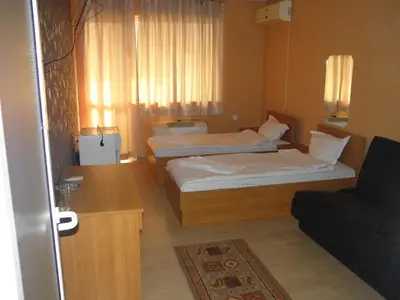 a hotel room with two beds and a couch at Hotel Pilevski in Blagoevgrad