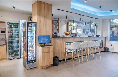 a restaurant with a bar with white chairs and a refrigerator at Hotel Pilevski in Blagoevgrad