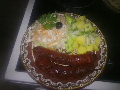 a plate of food with two sausages and vegetables at Guest House Todorini kashti in Koprivshtitsa