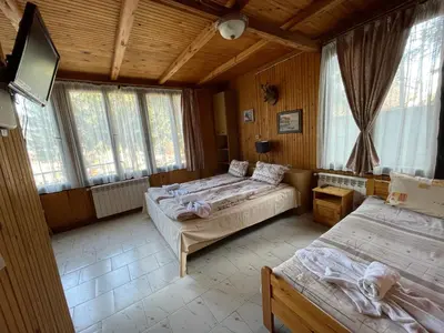 a bedroom with two beds and a tv and windows at Вила Мерджан in Sarnitsa