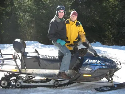 two men sitting on a snowmobile in the snow at Flora Ski-slope Studio Apartment in Borovets