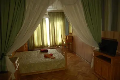 a bedroom with a bed and a television and curtains at Stivan Iskar Hotel in Sofia
