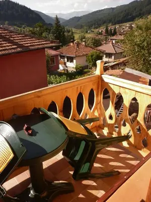 a balcony with a table and a view of a city at Guest House Mavrudieva in Koprivshtitsa