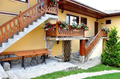 a house with a wooden staircase and a bench at Guest House Mavrudieva in Koprivshtitsa