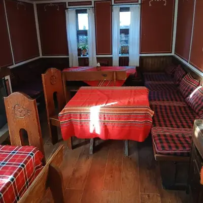 a restaurant with tables and chairs with red table cloth at Hadji Neikovi Guest Houses in Koprivshtitsa