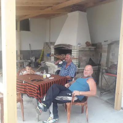 a group of men sitting at a table with a fireplace at Къща за гости Чала in Chala
