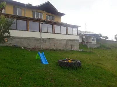 a yard with a tire and a playground in front of a house at Къща за гости Чала in Chala