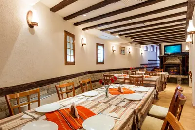 a dining room with tables and chairs and a television at Family Hotel Romantika in Velingrad