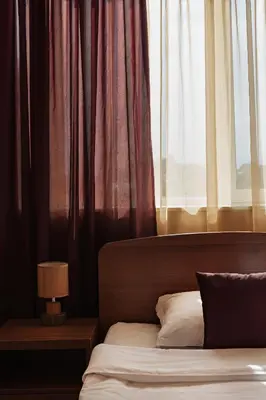 a bedroom with a bed and a window with curtains at Family Hotel Gerdjika in Plovdiv
