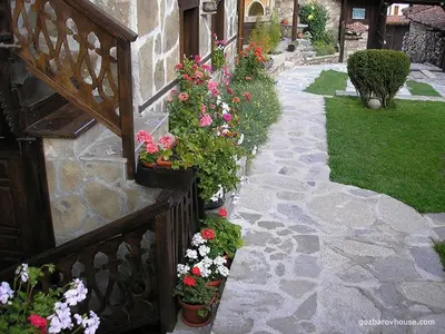 a garden with flowers on the side of a house at Gozbarov's Guest House in Koprivshtitsa